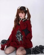 Model wearing a red loose gothic sweater with black spider web details and black boots.