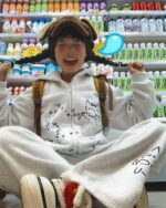 A person wearing a y2k kaomoji hoodie with cute character prints and a yellow backpack.