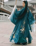 A teal embroidered jade hanfu, a Chinese Aesthetic garment, worn by a woman outdoors.