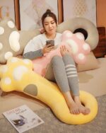 Cute Super Soft Cat Paw Pillow in gray and pink colors, resting on a floor.