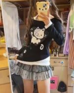 Patched Neko off-shoulder t-shirt featuring a cat graphic, displayed on a shelf.