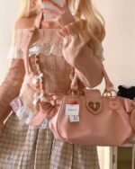 Close-up of a tan himekaji aesthetic sweater with off-shoulder detailing and a pink handbag.