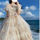 Cream floral lolita dress with ruffles and lace, outdoors by the sea.