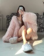 Pink puffy hooded coat worn by a person indoors.