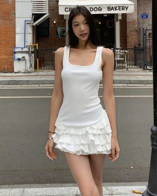 White ruffled coquette aesthetic dress worn by a woman outdoors.
