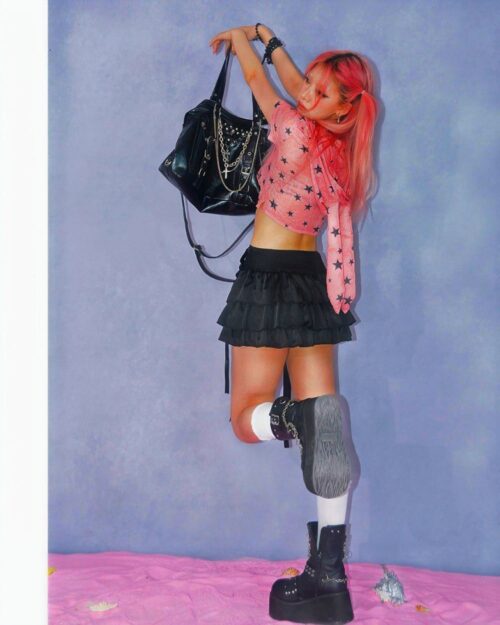 Person wearing a pink rabbit ears hooded t-shirt and layered edgy clothing.