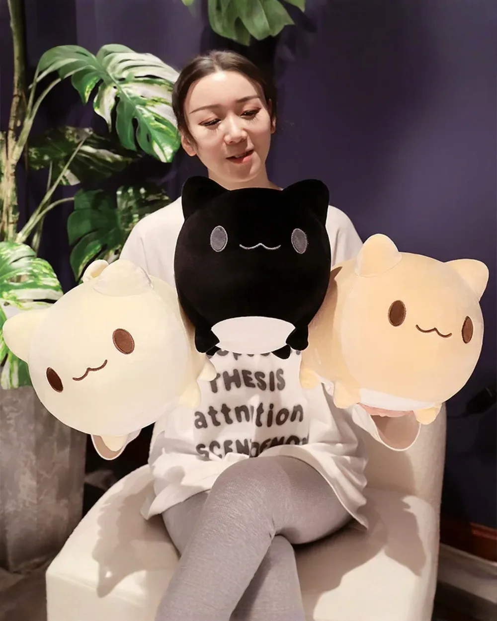 Two round neko plushies displayed next to a person. Cute kawaii plush toys.