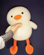 Close-up of a white kawaii duck plushie, Winston, with orange beak and feet.