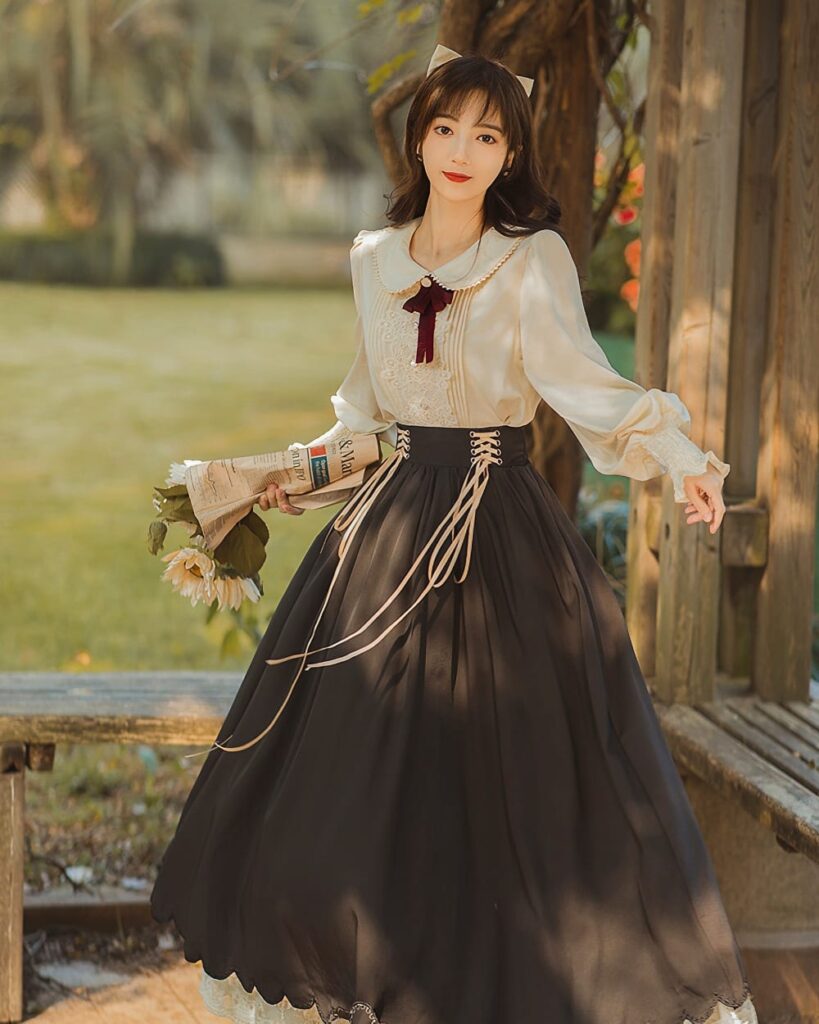 Woman wearing a black cottagecore dress with lace details and a long skirt outdoors.