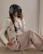 Woman wearing loose laced Korean aesthetic pants, headphones, and a backpack.