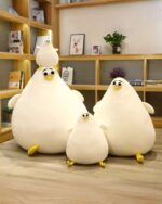 Two white round chicken plushies sitting on a shelf in a room.