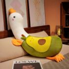 Soft yellow banana duck plushie with orange feet and beak, resting on a bed.