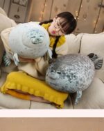Two Yuki the Seal Plush toys resting on a couch with a child.