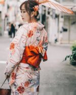 Woman wearing a floral summer anime yukata in a Japanese street setting.