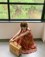 Woman wearing a red and brown french vintage suspender skirt, holding a suitcase.