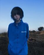 Person wearing a blue japanese sporty jacket outdoors.