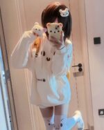 Person wearing a white kaomoji bear hoodie with paw print socks and bear hair clips.