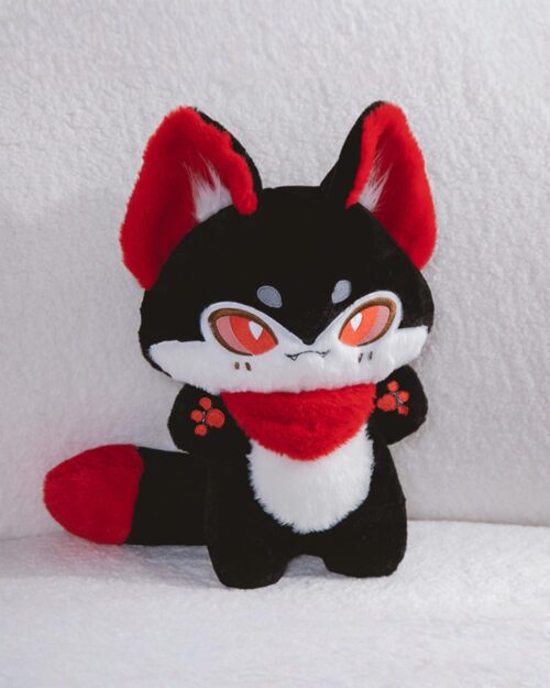Kawaii little kitsune fox plushie, black and red, sitting on a white surface.