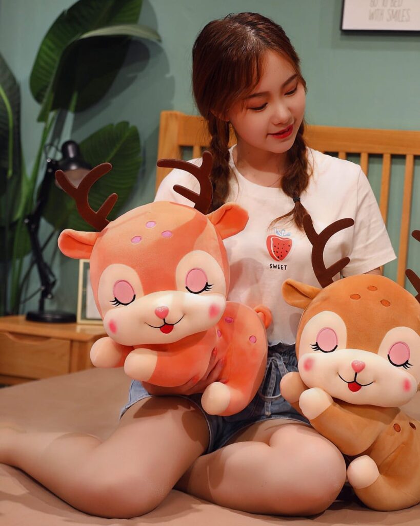 Two soft baby deer plushies with brown fur and antlers, displayed on a bed.