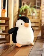 A soft, chonky penguin plushie, Pip, with a black and white design and orange beak.