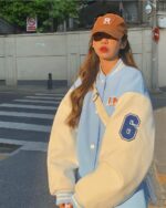 Woman wearing a Korean aesthetic jacket and baseball cap on a city street.