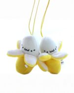 Two kawaii chibi banana plushies hang on yellow strings, perfect for a fruit keychain.