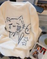 White neko sweater with a fluffy, embroidered cat design featuring stars and a heart.