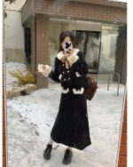 Woman wearing a french aesthetic outfit, including a wool coat and skirt with fur trim, outdoors in snow.