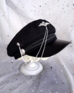 Close-up of a gothic style army hat with silver chain and star details on a white base.