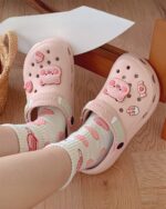 Pink pig-shaped piggy crocs slippers with a cute design on the strap.