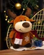 Cute brown reindeer christmas plushie decor displayed near a Christmas tree.