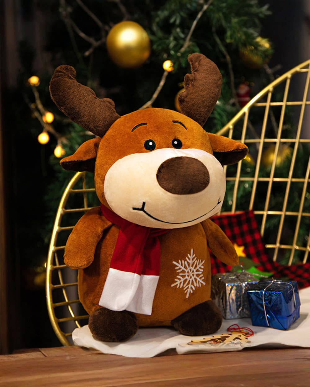 Cute brown reindeer christmas plushie decor displayed near a Christmas tree.
