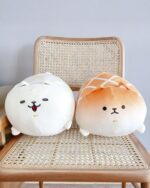 Two melonwan dog plushies, one white and one orange, sitting on a chair.