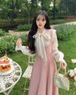 Model wearing a long pink vintage aesthetic dress outdoors.