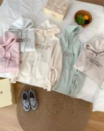 Several Romantic Long Island zipper hoodies in pink, blue, and gray are displayed, alongside sneakers and fruit.
