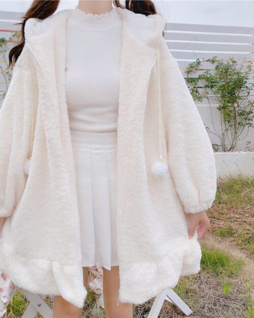 Cream-colored plush rabbit hoodie with a hood and pom-pom details.