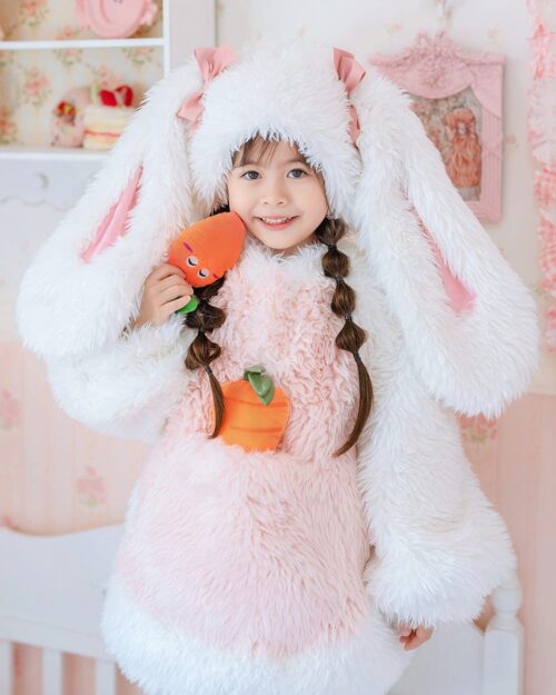 Child wearing an Easter bunny costume with a carrot. Includes a matching bunny hat and fur-trimmed jacket. #easterbunnycostume
