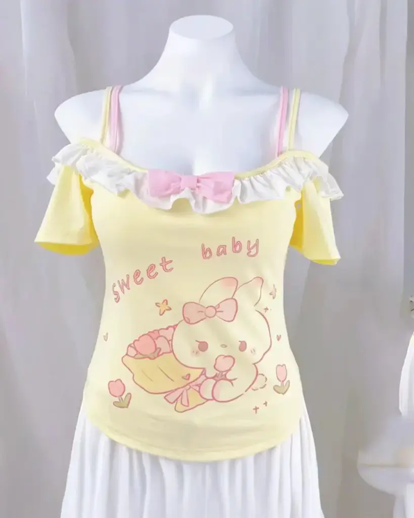 Yellow yume kawaii crop top featuring cute cartoon animals and bows. It has ruffled sleeves and a cropped design.
