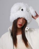 Woman wearing a white fluffy eyed hat, a playful winter accessory.