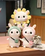 Three kawaii bunny plushies, including one with a hat, arranged on a wooden surface.