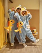 Two people wearing blue dino-shark jumpsuit costumes with plush toys. Couple edition pajama jumpsuit.