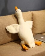 A large, soft, white big goose plush toy resting on a beige couch.