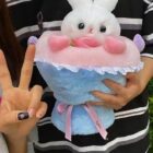 Close-up of a bouquet rabbit plushie featuring a pink and blue design with ruffles and ribbon.