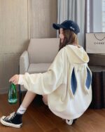 Cream-colored bunny ear hoodie worn by a person, featuring long, blue bunny ears.