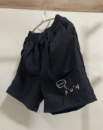 Black kaomoji aesthetic shorts hanging on a hanger. Cotton material.