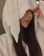 Person wearing fluffy bunny pajamas with a hood, soft girl aesthetic.
