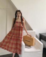 Woman wearing a red and black plaid french vintage suspender skirt, posing indoors.