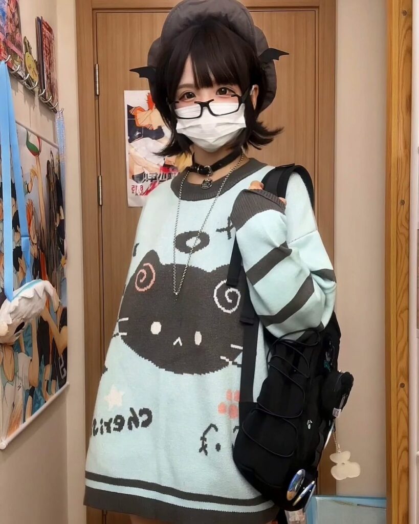 Person wearing a mint neko sweater with a black cat graphic. Harajuku aesthetic.