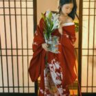 A red aesthetic kimono with floral patterns, worn by a woman indoors.