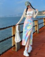 Colorful y2k denim skirt with side slits, worn casually by the water.